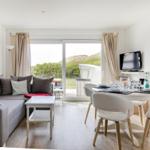 Living and dining area with sofa, table, and view of garden.