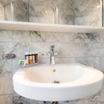 Sink with mirror and soap bottles on marble wall