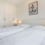 Bedroom with double bed, white walls, and wardrobe. Wall picture shows lighthouse.