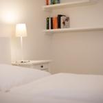 Bedroom with white bed, nightstand, and bookshelf.