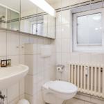 Bathroom with sink, mirror, toilet, and radiator.