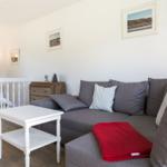 A living room with a gray sofa, white table, and pictures on the wall.