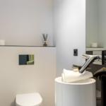 Badezimmer mit Waschbecken, Spiegel, Toilette und Handtuch