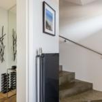 Haus mit Treppe, Spiegel und modernem Kunstwerk an der Wand.