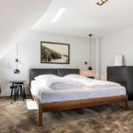 Schlafzimmer mit Doppelbett, Kleiderschrank und Wandbild.