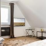 Schlafzimmer mit Dachschräge, TV, Fenster und Möbeln.