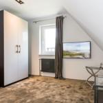 Schlafzimmer mit Kleiderschrank, Fenster, TV und Glas-Tisch.