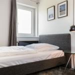 Schlafzimmer mit Bett, Fenster, Bildern und Tisch