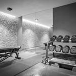 Fitnessraum mit Hanteln, Bank und Spiegelwand.