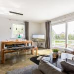Wohn- und Essbereich mit Holztisch, Sofa und Fernseher. Durchgangstür zum Garten.