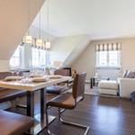 Dining area with table and chairs. Living room with sofa and windows.