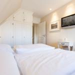 Room with double bed, white wardrobes, and wall-mounted TV.