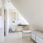 Bathroom with shower, sink, and toilet under sloped ceiling