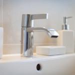 Sink with modern faucet and white accessories.