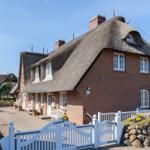 Red brick building with thatched roof and white gate.