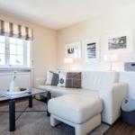 Living room with white sofa, glass table, and window with roller blind.