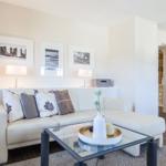 Living room with white sofa, glass table, and wall art.