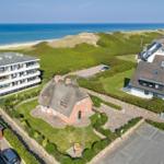 Haus mit Strohdach, Grünanlagen und Blick aufs Meer.