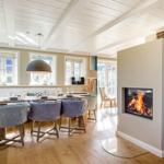 Esszimmer mit Feuerkamin und Holzboden. Tisch mit Stühlen und Fenstern.