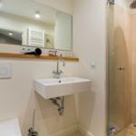 Badezimmer mit Waschbecken, Spiegel und Dusche.