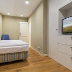 Schlafzimmer mit Bett, Fernseher und Holzboden.
