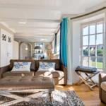 Wohnzimmer mit Sofa, Sitzbank und großem Fenster. Holzboden und blaue Vorhänge.