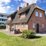 Rotes Backsteingebäude mit strohgedecktem Dach und Garten