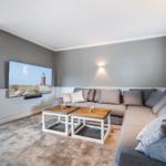 Living room with sectional sofa, TV, and two coffee tables on carpet.