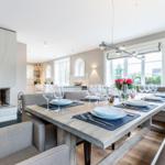 Dining area with dining table, bench, and fireplace. Windows with view outside.