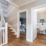 House with wooden staircase, living room, and bathroom in hallway.