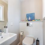 Bathroom with sink, mirror, and toilet. Wall art with sailboats and decorative fish.