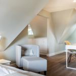 Bedroom with armchair, desk, and sloped ceiling