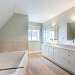 Bathroom with bathtub, sinks and wooden floor
