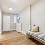 Hallway with bench, cabinet, and window. Wooden floor and white walls.