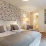 Bedroom with bed, bird-patterned wallpaper, and white wardrobe.