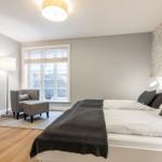 Bedroom with bed, window, TV, and seating area.