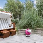 Deck with beach chair and pink sheep sculpture in front of greenery