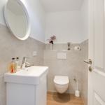 Badezimmer mit Waschbecken, Toilette und runden Spiegel an der Wand.