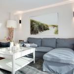 Ein Wohnzimmer mit grauem Sofa, weißem Couchtisch und Wandbild.
