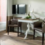 Dining area with table, two chairs, and TV mounted on the wall.