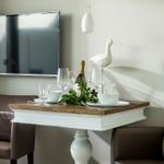 Dining table with glasses, bottle, and bird decoration in front of TV