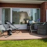 Terrace with lounge chairs, table and chairs. View into the interior of the house.