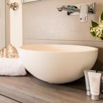 Sink with seashell, towels, and flowers on wooden countertop.