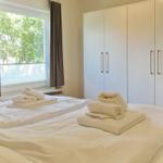 Two beds with white bedding and folded towels. Trees are visible outside the window.