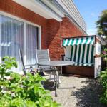 Terrace with lounge chair, table, and beach chair beside red brick house.