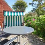 Terrace with table, chairs, and beach chair in front of red brick house.