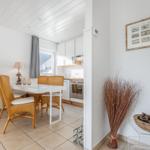 Dining area with table, chairs, and kitchen area in the background.