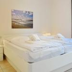 Bedroom with white bed, nightstand, and wall picture.