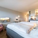 Bedroom with double bed, kitchen area, and armchair.