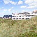 Modern building with balconies behind dunes and flag in background.